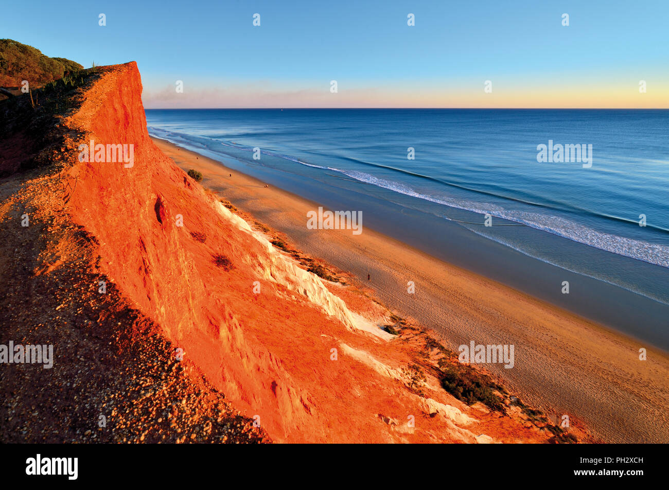Soirée à l'atmosphère pittoresque de long plage de sable avec du sable rouge des falaises et l'océan calme Banque D'Images