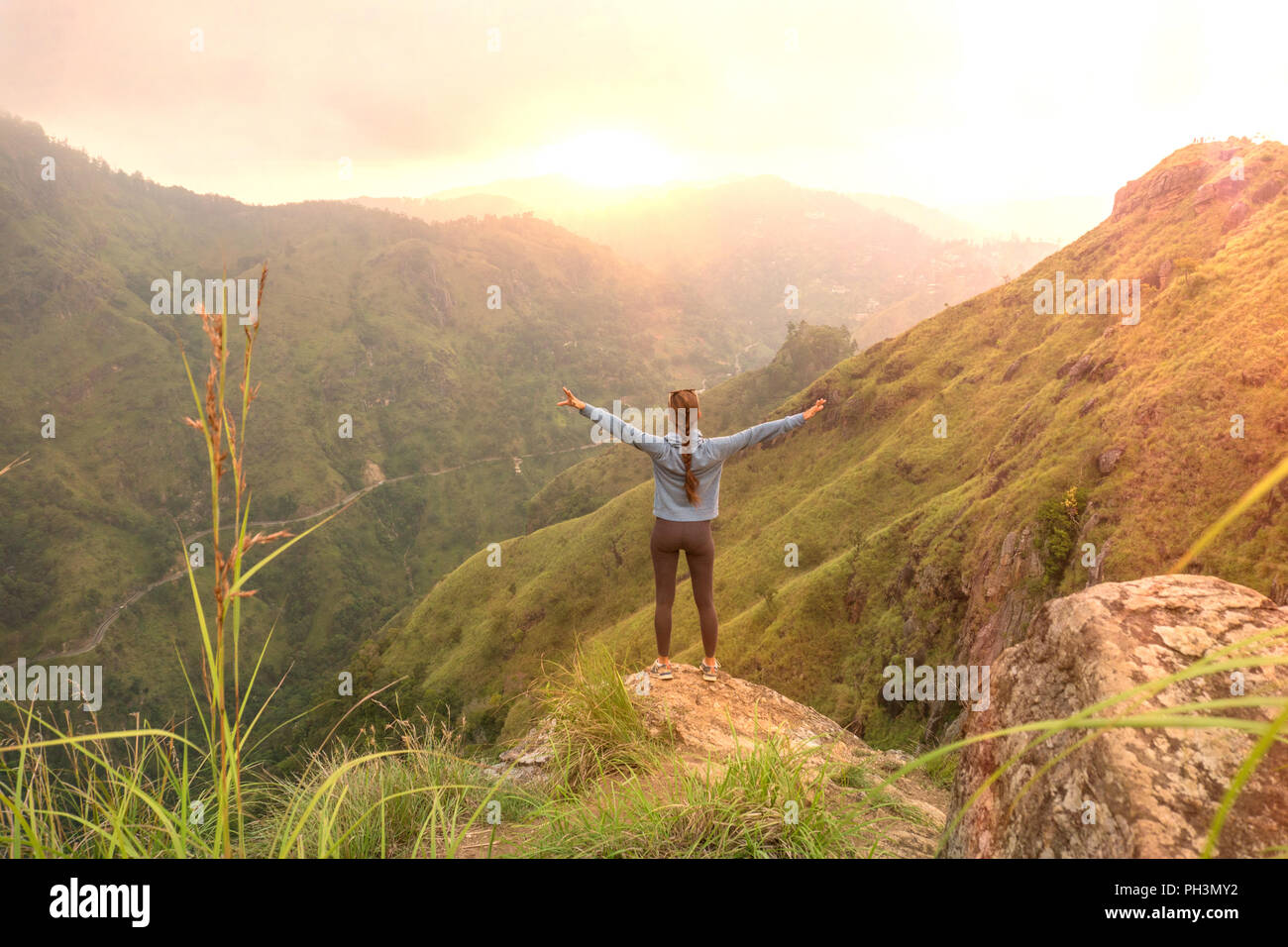 Femme sportive debout avec les bras levés en haut oh Hill à la recherche au lever du soleil. Banque D'Images