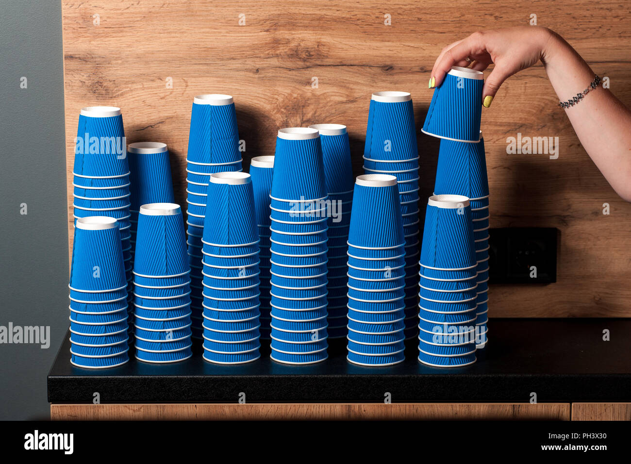 Femme barista prend un verre de papier, de nombreux moulins dans une pile Banque D'Images