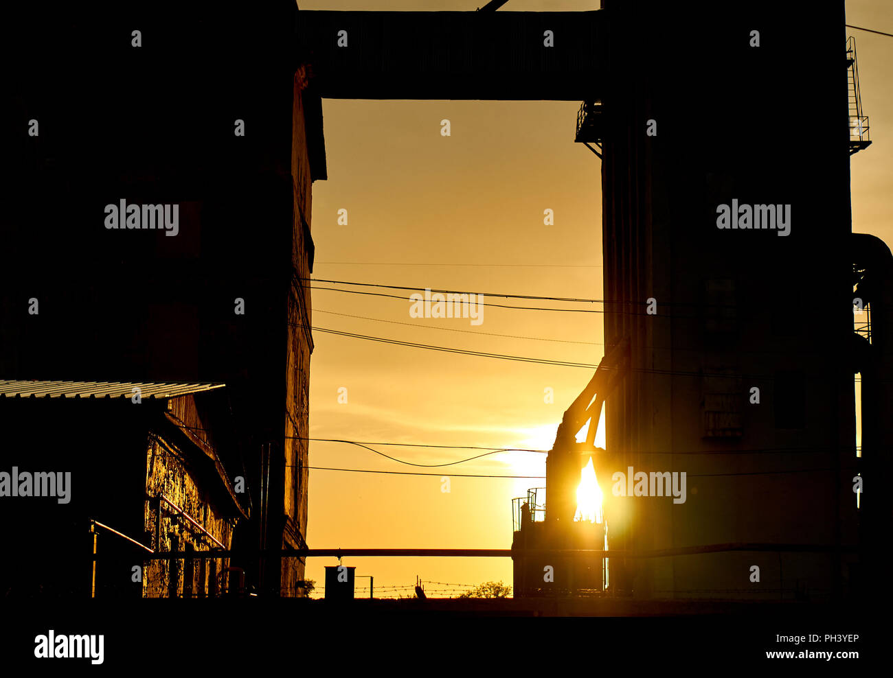 Grande silhouette de plusieurs bâtiments d'usine dans la zone industrielle isolée sur le coucher du soleil Banque D'Images