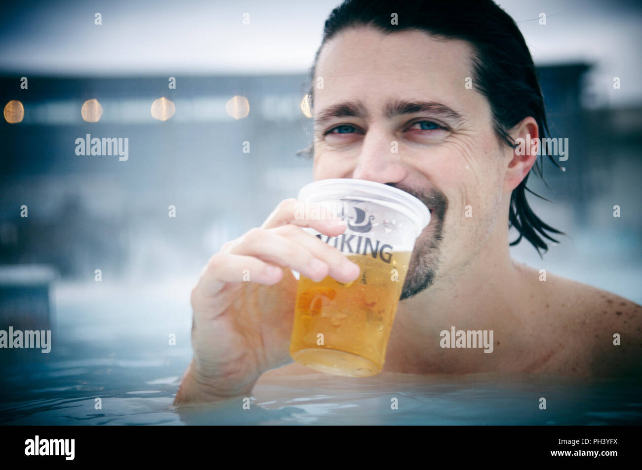 Un homme jouit d'une bière Viking dans les sources chaudes du Lagon Bleu, l'Islande. Banque D'Images