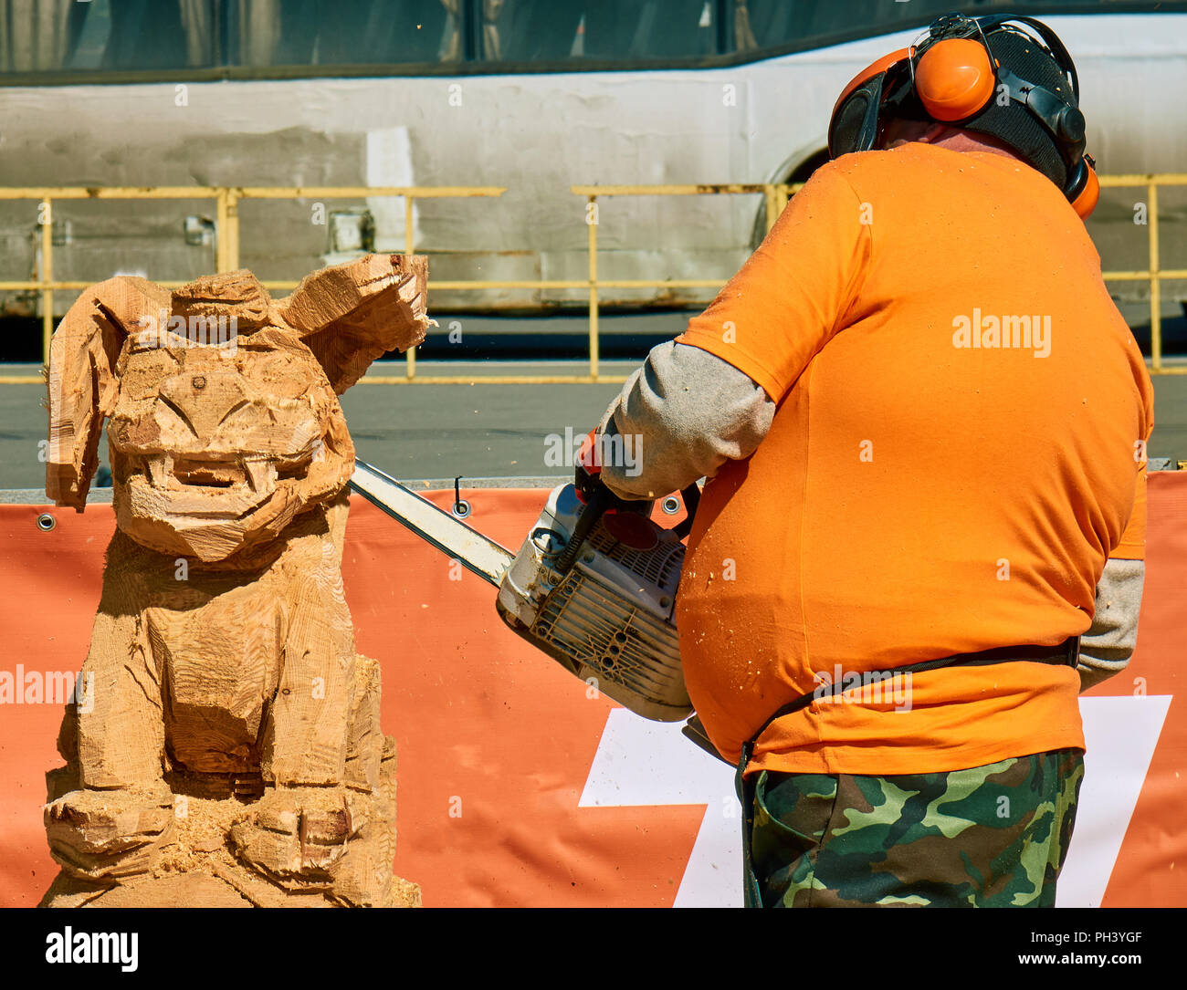 Menuisier expérimenté de faire un gros chien en bois sculpture avec une tronçonneuse lors d'une concurrence locale, presque fini Banque D'Images