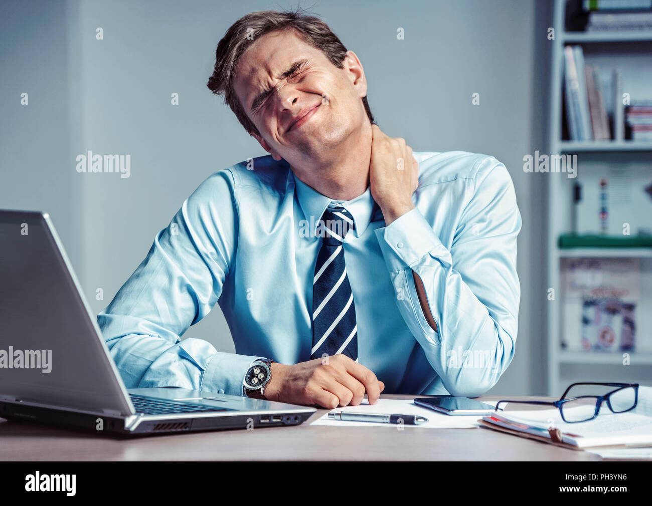 Employé souffre d'une douleur dans le cou. Photo d'un homme travaillant au bureau. Concept médical. Banque D'Images