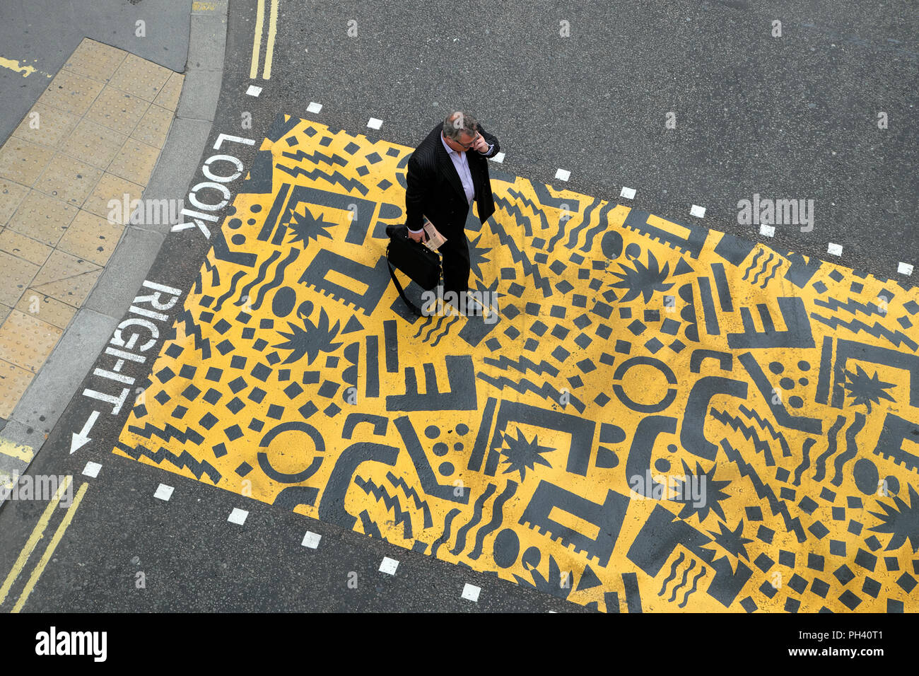 Art géométrique Kishimoto et businessman walking with briefcase sur jaune passage piétons près de Aldersgate, dans la ville de London, UK KATHY DEWITT Banque D'Images