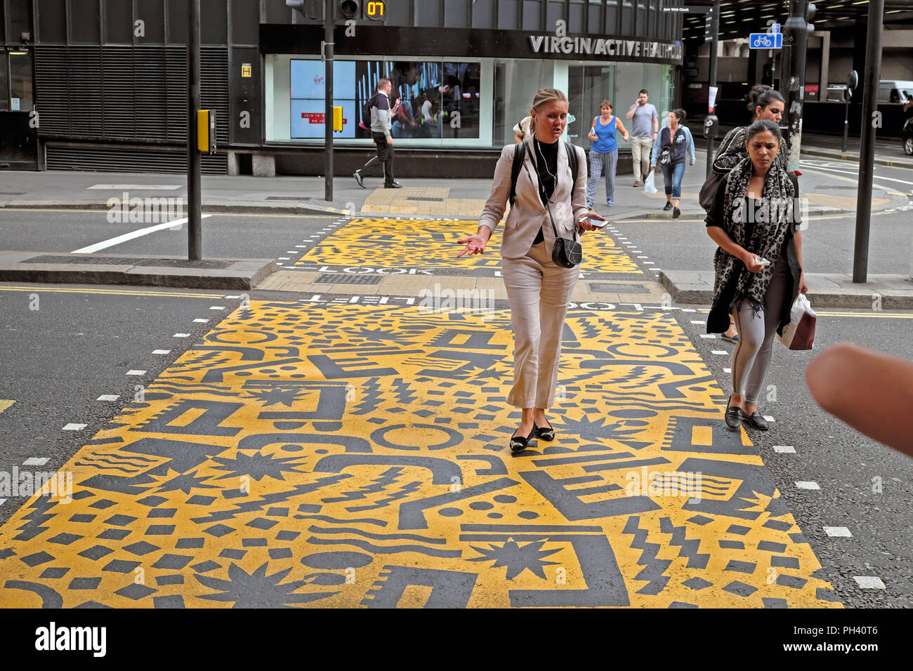 Kishimoto illustrations et géométrique qui marche sur les jeunes femmes jaune route passage piétons près de Barbican station dans la ville de London UK KATHY DEWITT Banque D'Images