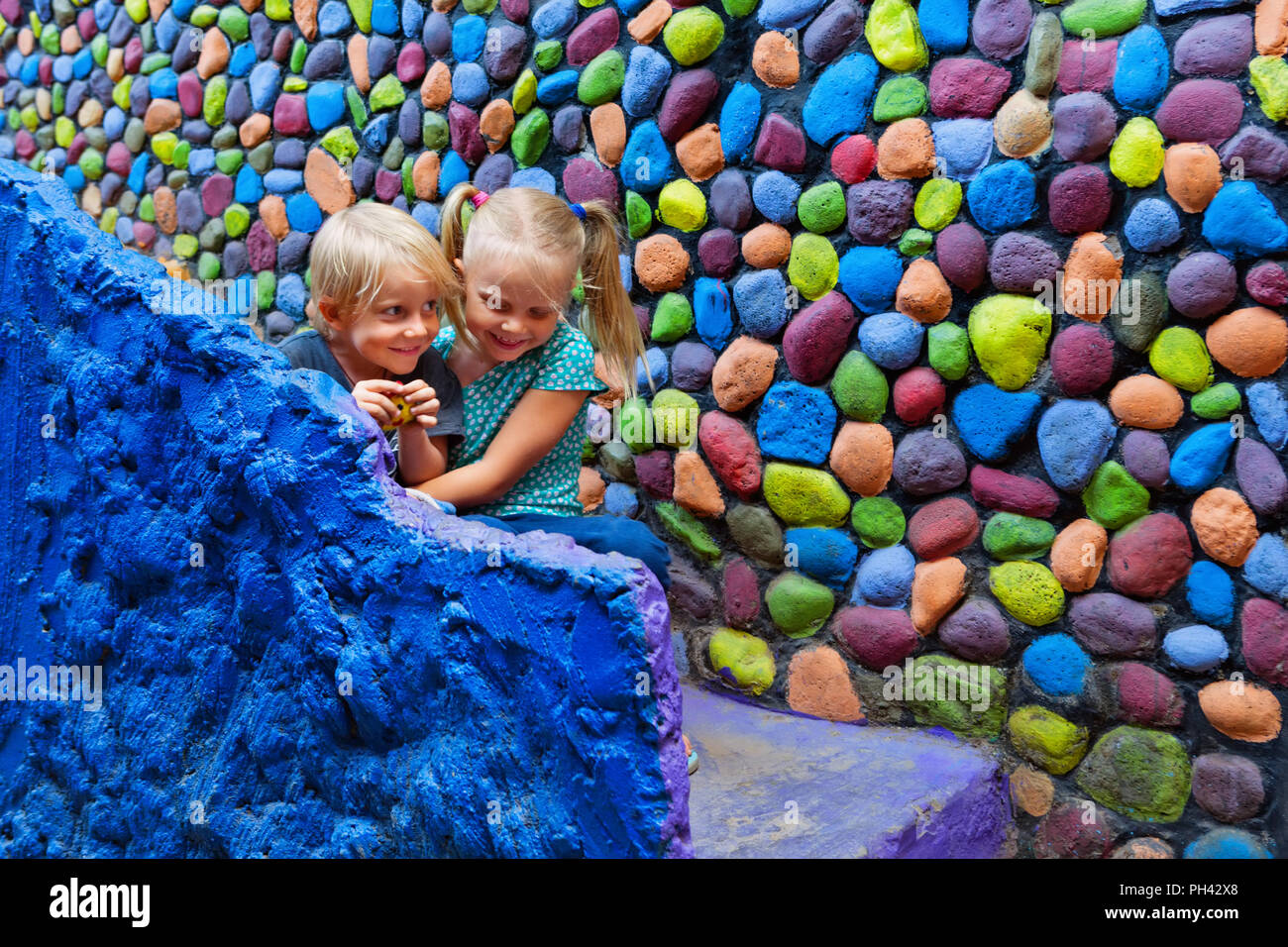 Deux enfants heureux s'amusent ensemble assis dehors sur les marches en pierre colorée d'accueil. Playful girl hug rire jeune frère. Vie de voyage, randonnée pédestre ci Banque D'Images