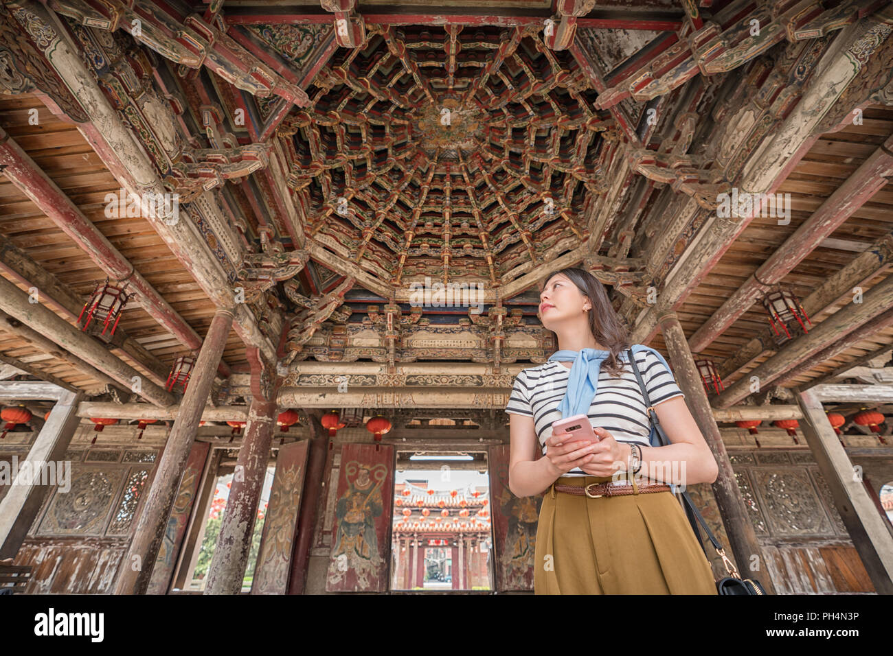 Asian woman standing dans le vieux beau temple. tenant un mobile dans les mains Banque D'Images