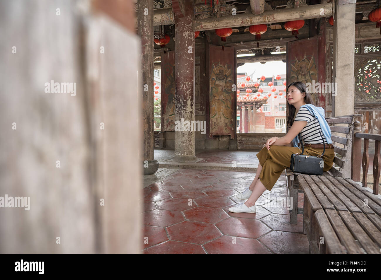 Vue de côté de femme d'origine asiatique assis sur le banc. Banque D'Images