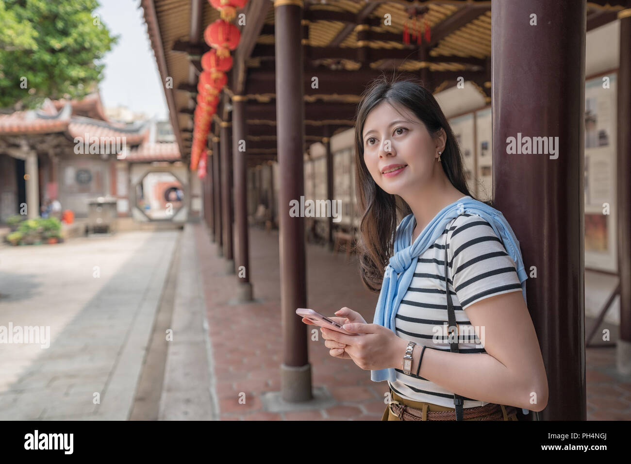 Vue latérale d'asian woman holding a smartphone. à la recherche d'une visite Banque D'Images