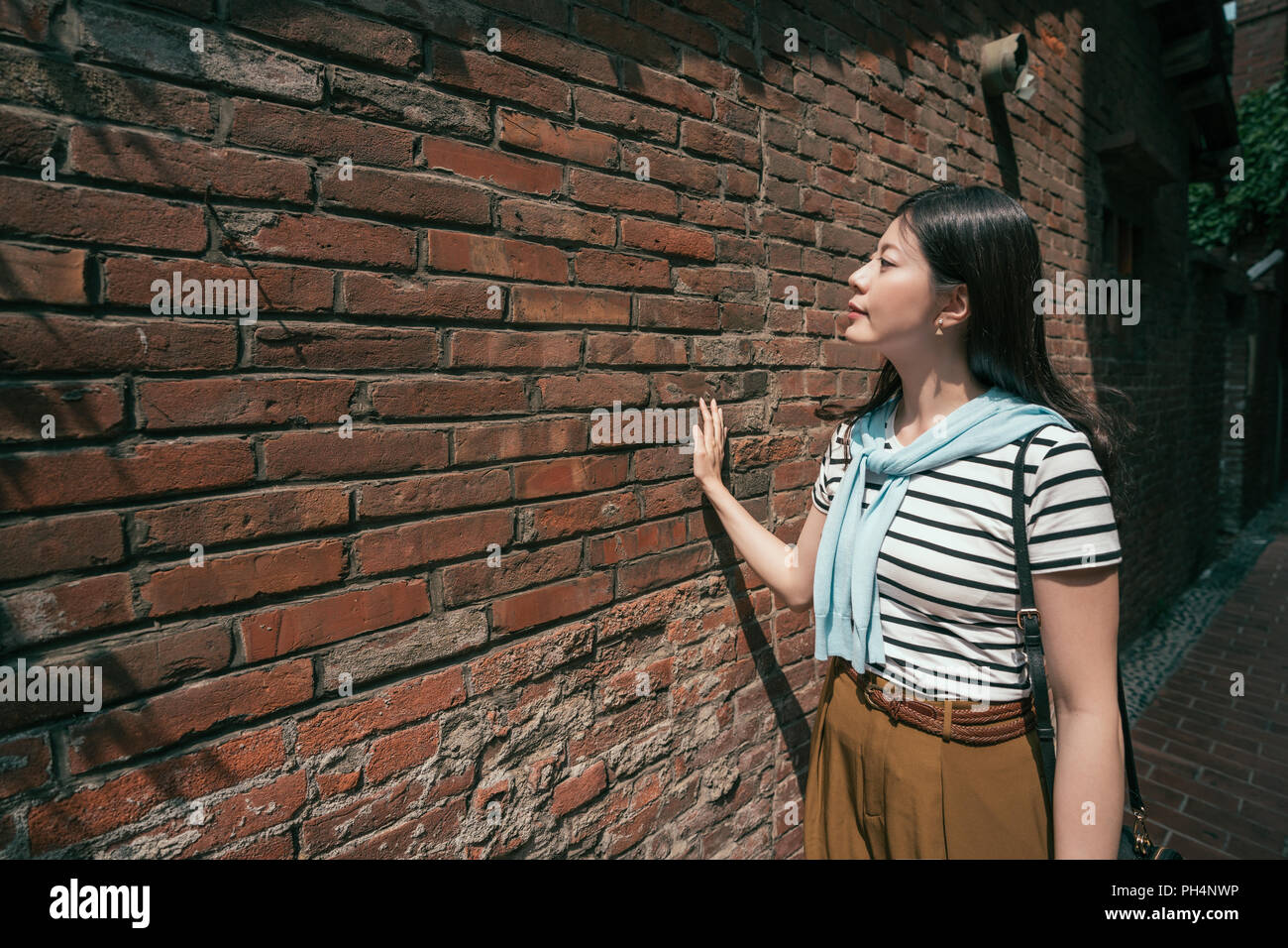 Belle femme debout à côté du mur. smiling et voir la vue Banque D'Images