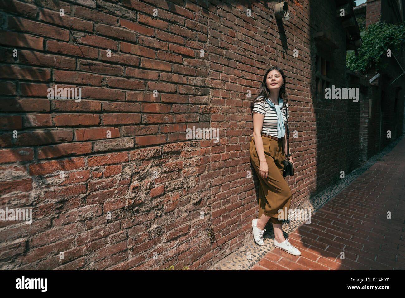 Belle femme s'appuyant sur le mur. debout dans la vieille rue. Banque D'Images