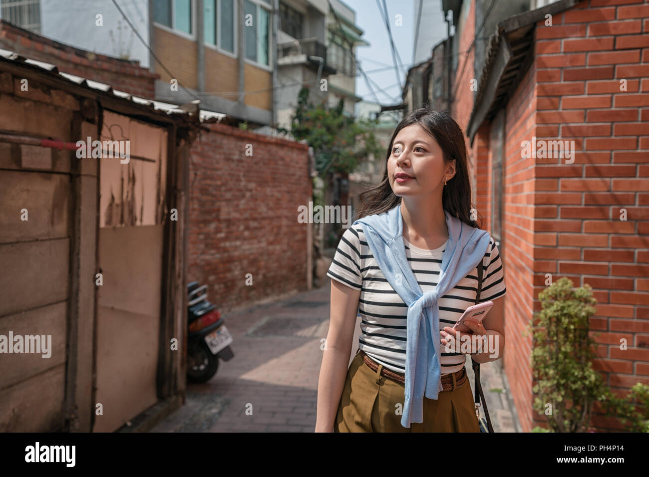 Visiteur se promener dans l'allée par holing a téléphone. alley entourée de maisons anciennes. Banque D'Images