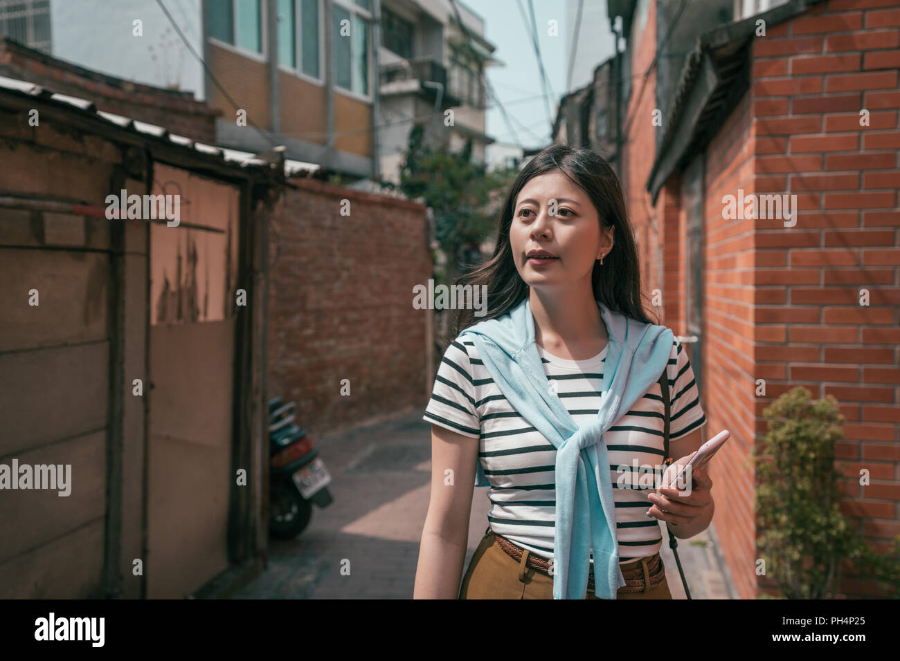 Visiteur asiatique flâner dans la vieille rue. Femme tenant un téléphone. Banque D'Images