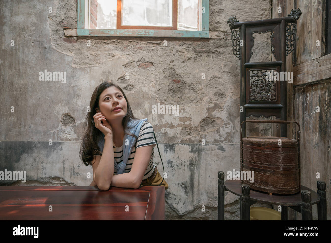 Jolie femme assis dans la vieille maison traditionnelle. avec l'arrière-plan de l'ancien artisanat traditionnel. Banque D'Images