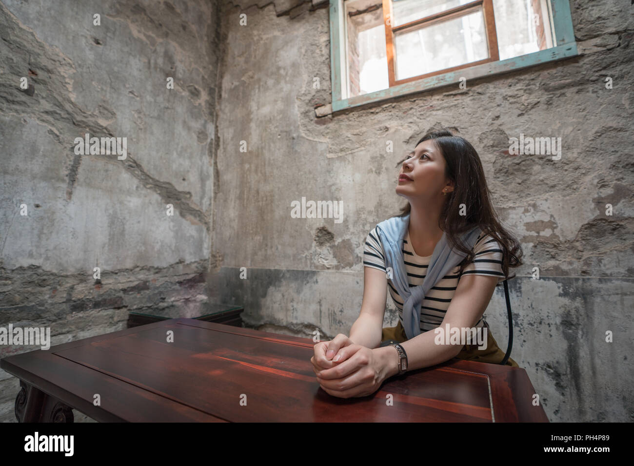 Asian female siiting dans la vieille maison. avec l'arrière-plan de mur. Banque D'Images