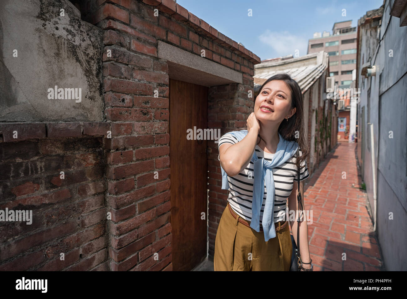 Femme à la recherche vers le haut de la ruelle étroite. entourée de maisons anciennes. Banque D'Images
