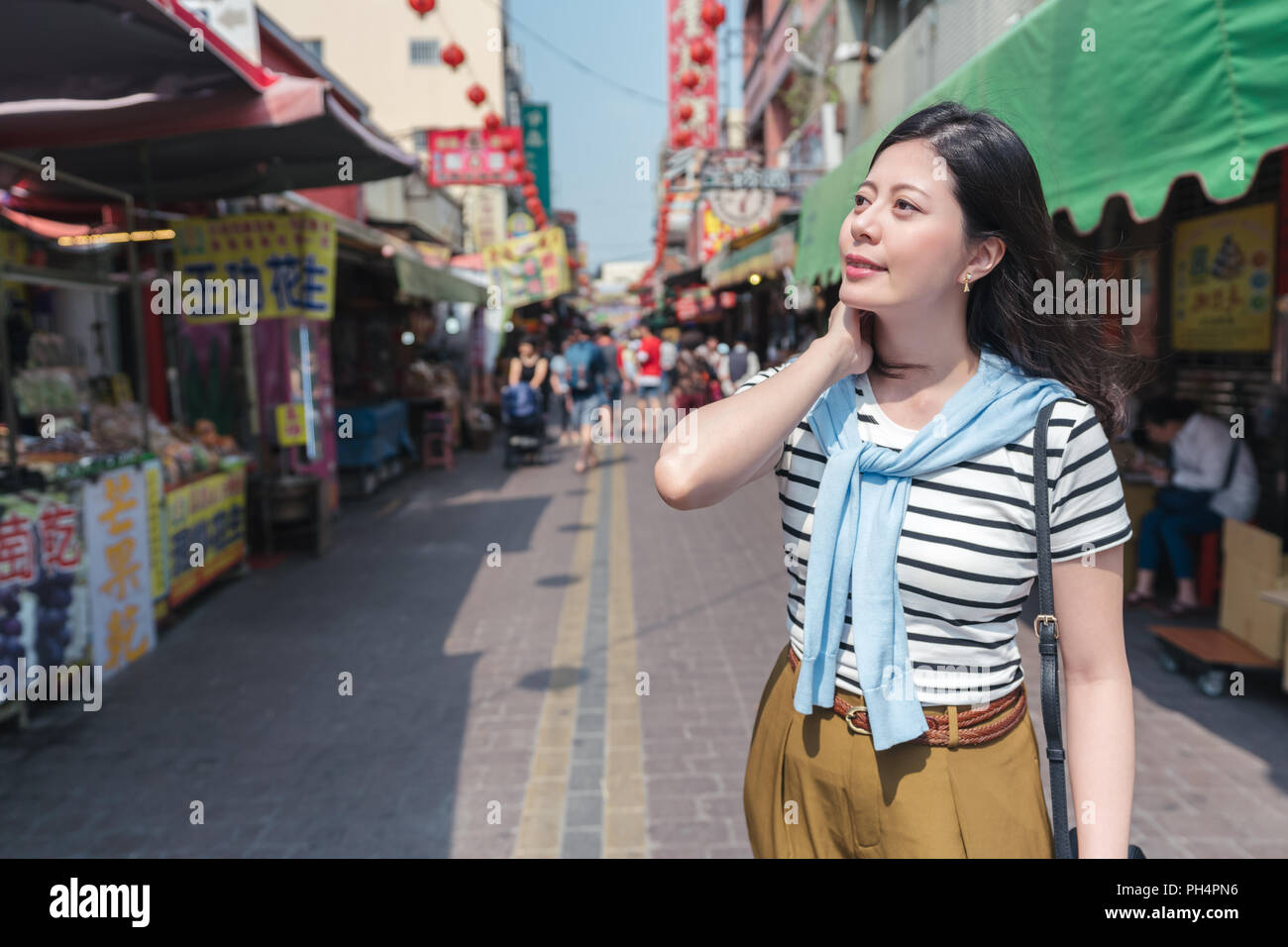 Asian female smiling et debout dans la rue. avec l'arrière-plan du marché. Banque D'Images