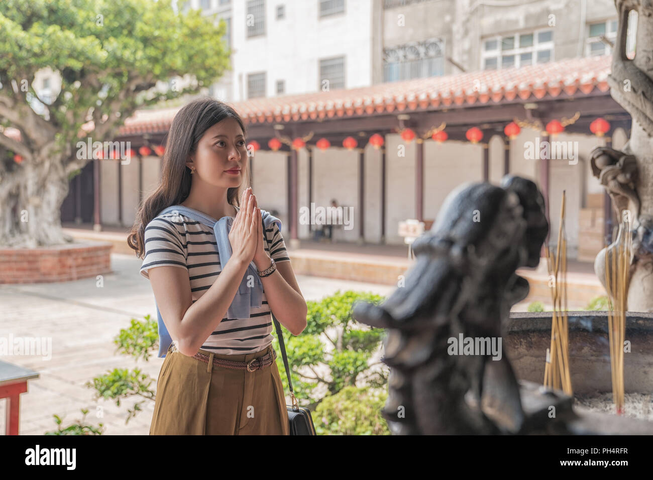 Asian woman praying fidèlement dans le Temple. Un rituel traditionnel dans la culture chinoise. Banque D'Images