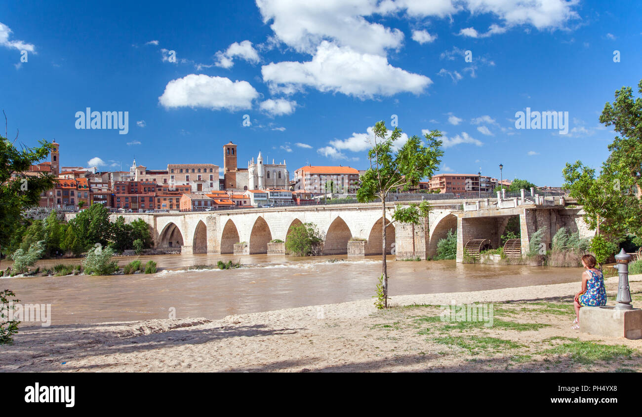 Femme assise par jet d'eau sur la plage par l'homme sur le fleuve Douro avec une vue sur la ville médiévale de Tordesillas dans la distance Espagne Banque D'Images