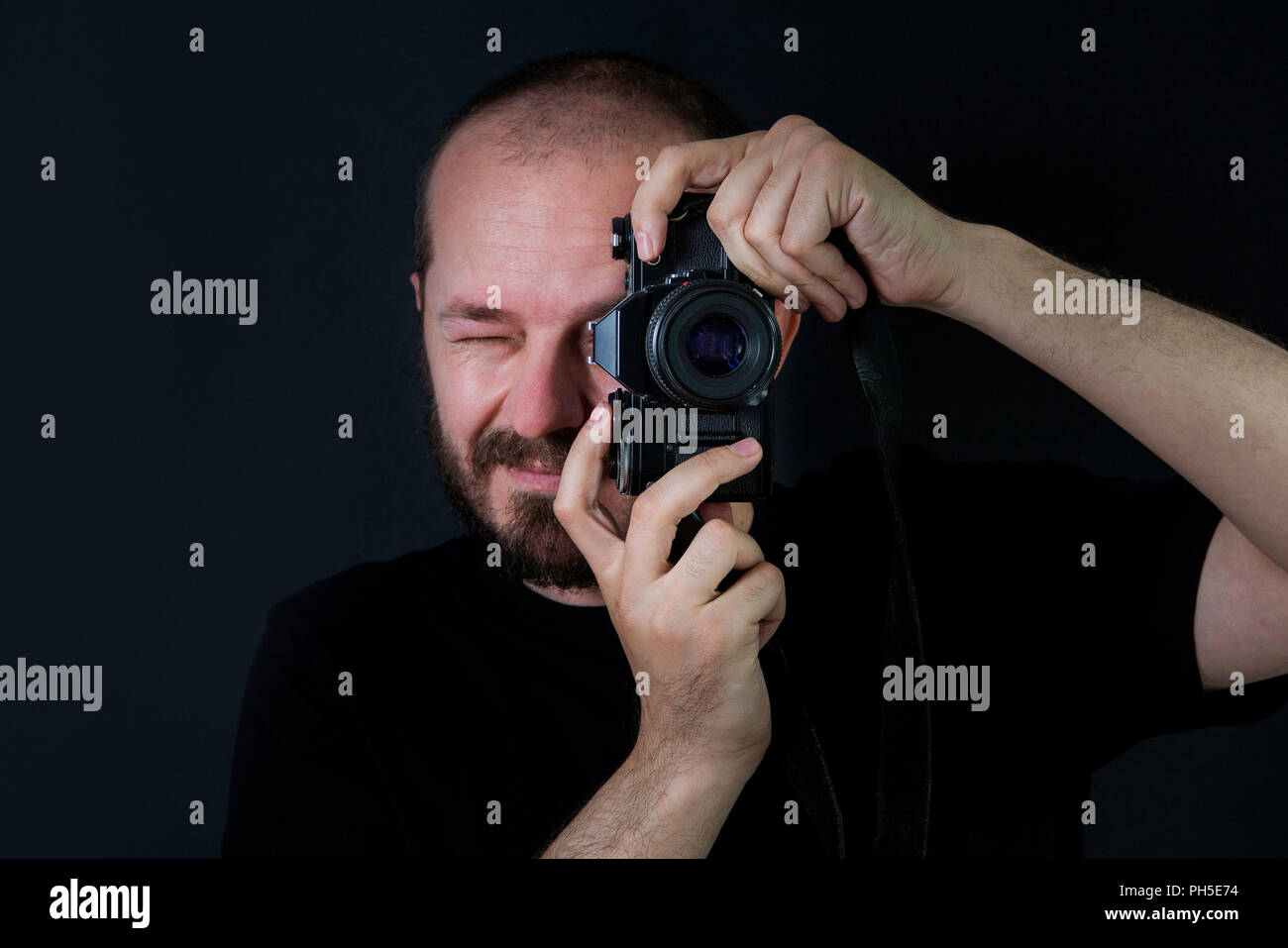 L'homme sur fond noir en bas-clé, tenant des photos de caméra analogique et Banque D'Images