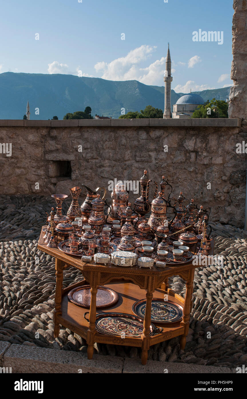 Bosnie : une petite table avec plateau en cuivre typique et café à vendre et point de vue sur les toits de Mostar avec la Mosquée Koski Mehmed Pacha Banque D'Images