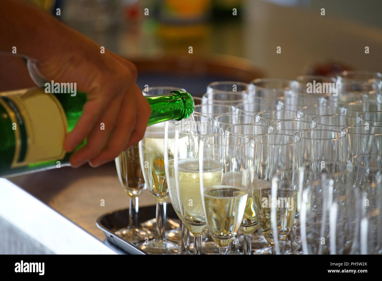 Main tenant une bouteille de vin mousseux, verser le champagne dans les tasses Banque D'Images