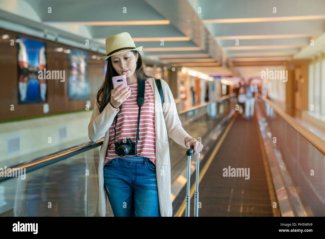 Visiteur à l'aide du smartphone sur le plancher escalator tunnel passerelle arrière-plan dans l'aéroport. Banque D'Images