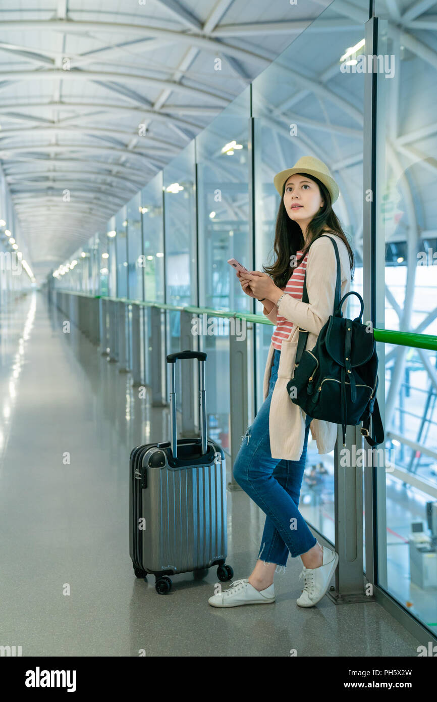 Woman leaning on les garde-corps en verre. tenant son téléphone et à échouer. Banque D'Images