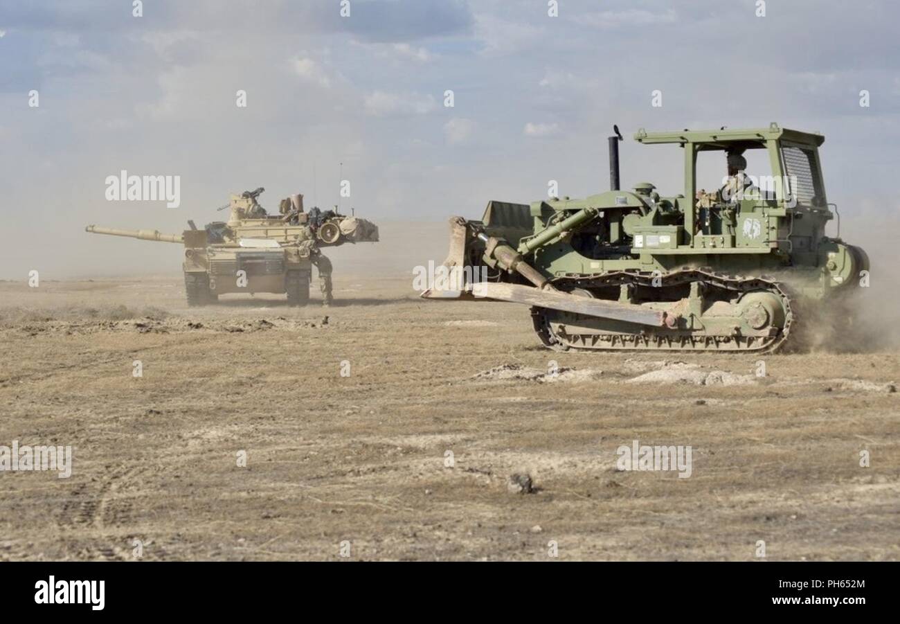 Un ingénieur de la Compagnie A, 116e bataillon du génie de la Brigade passe devant un M1A2 Abrams char de combat principal de construire des positions de combat pour la garde nationale de l'Oregon a une compagnie, 3-116ème Bataillon interarmes, 20 juin 2018, au cours de la 116e Brigade de cavalerie de l'Équipe de Combat Combat eXportable capacité de formation en alternance au centre de formation de combat du verger. T Banque D'Images