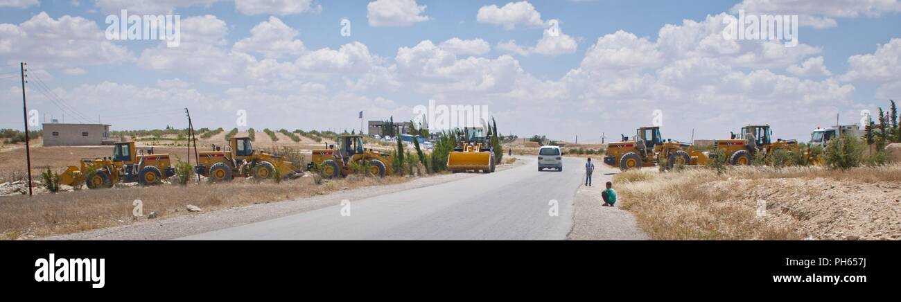 Le personnel militaire américain créer un blocus à l'aide de chargeuses et de camions sur une route en direction de Manbij, Syrie, 20 juin 2018. Le blocus est conçu pour permettre la circulation locale par l'intermédiaire de l'établissement peut être fermé immédiatement si nécessaire. Les États-Unis et les forces turques mènent des patrouilles coordonnées, indépendant à l'extérieur de Manbij pour assurer la sécurité de la ville. Banque D'Images