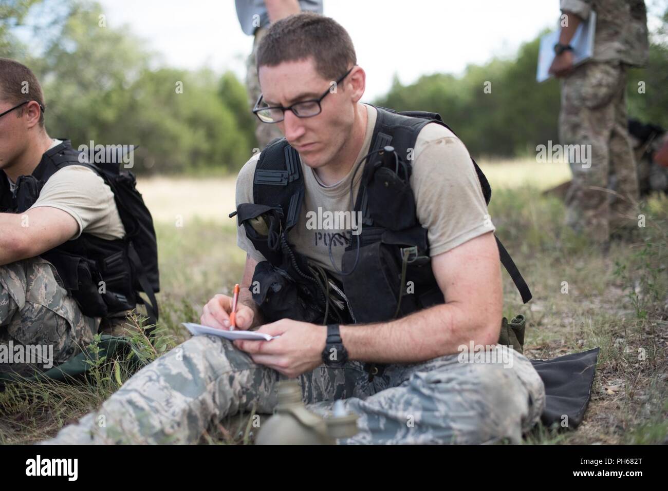 Un stagiaire qui cherchent à devenir la survie, évasion, résistance, et échapper à ses revues spécialisées Documents d'étude, avant que d'autres instructions SERE lors d'un ruck mars à JBSA-Camp Bullis, Texas. Banque D'Images