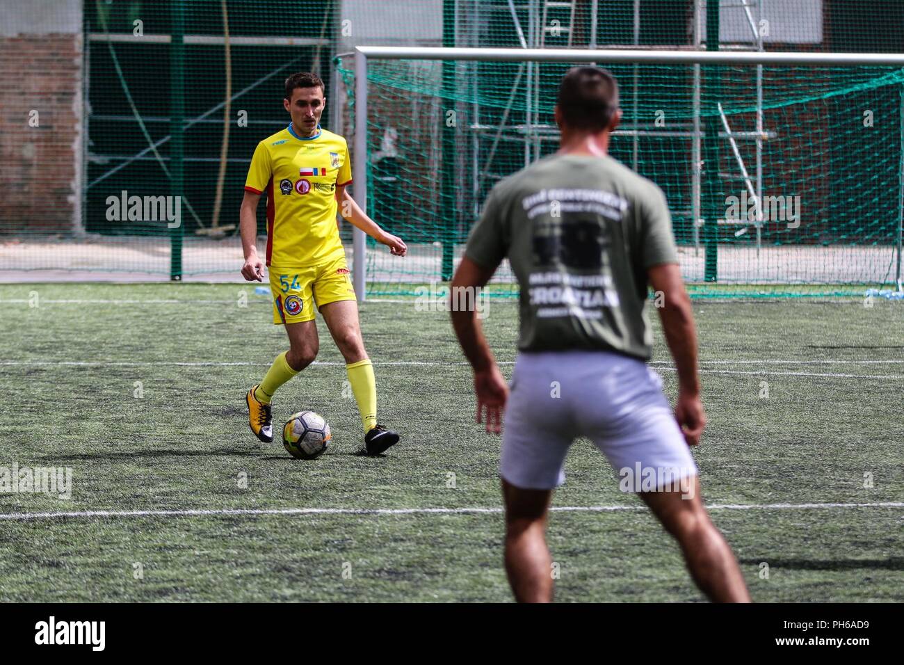Un soldat roumain avec l'artillerie de défense aérienne "Scorpions" bleu Batterie (jaune) tente de frapper un ballon de soccer au-delà d'un soldat de l'armée croate avec fusée d'artillerie "Tempête" de batterie (vert), dans le cadre d'une compétition sportive de groupe de combat avec la Pologne pour célébrer la Journée des Forces armées britanniques à Bemowo Piskie Domaine de formation, la Pologne, le 30 juin 2018. La Pologne est un groupe de combat, unique coalition multinationale d'États-Unis, Royaume-Uni, croate et soldats roumains qui servent avec la 15e Brigade mécanisée polonaise comme une force de dissuasion de l'OTAN à l'appui de l'amélioration de l'avant la Présence. Banque D'Images