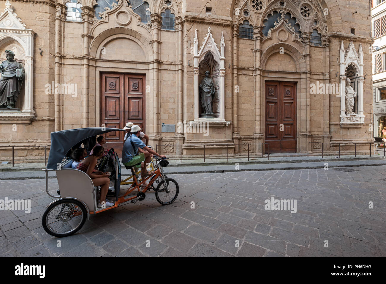 Florence, Italie - 2018, 14 juillet : les touristes sur une visite guidée, sur pedicab, visiter l'église Orsanmichele, dans le centre historique de Florence, Italie. Banque D'Images