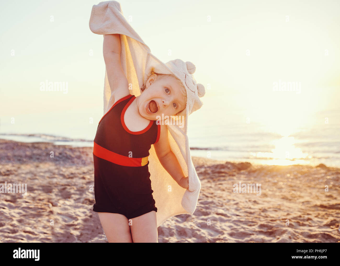 Portrait of cute adorable bambin happy smiling little Girl with towel on beach faire faces pose d'avoir l'amusement, l'expression émotionnelle face, style de su Banque D'Images