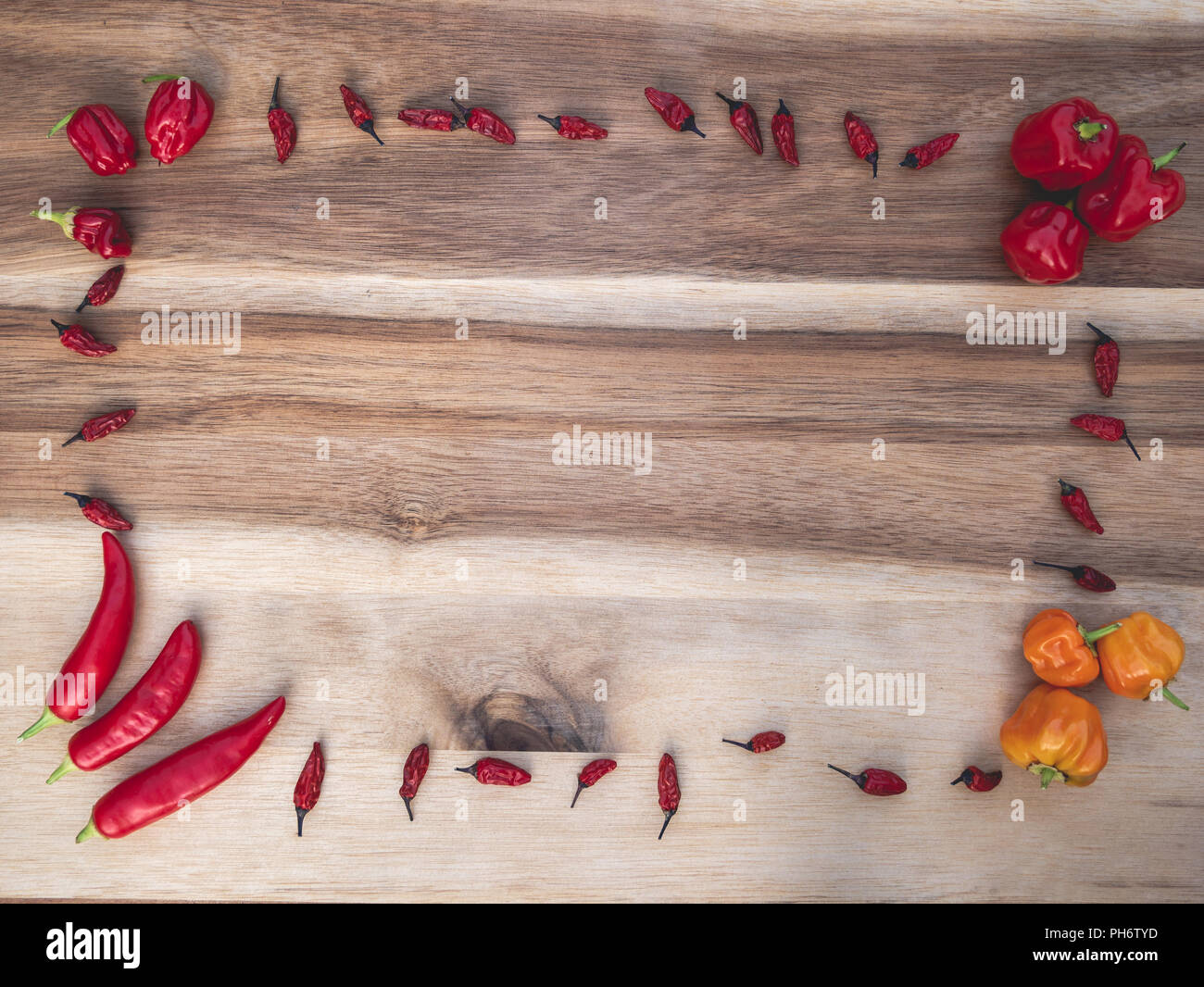 Cadre de différents types de piments rouges et orange sur une planche en bois Banque D'Images