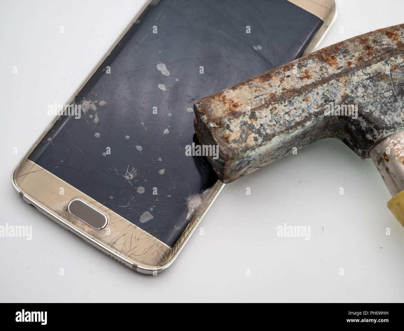 Close-up d'affichage de votre smartphone est endommagée à l'aide d'un marteau et fond blanc Banque D'Images