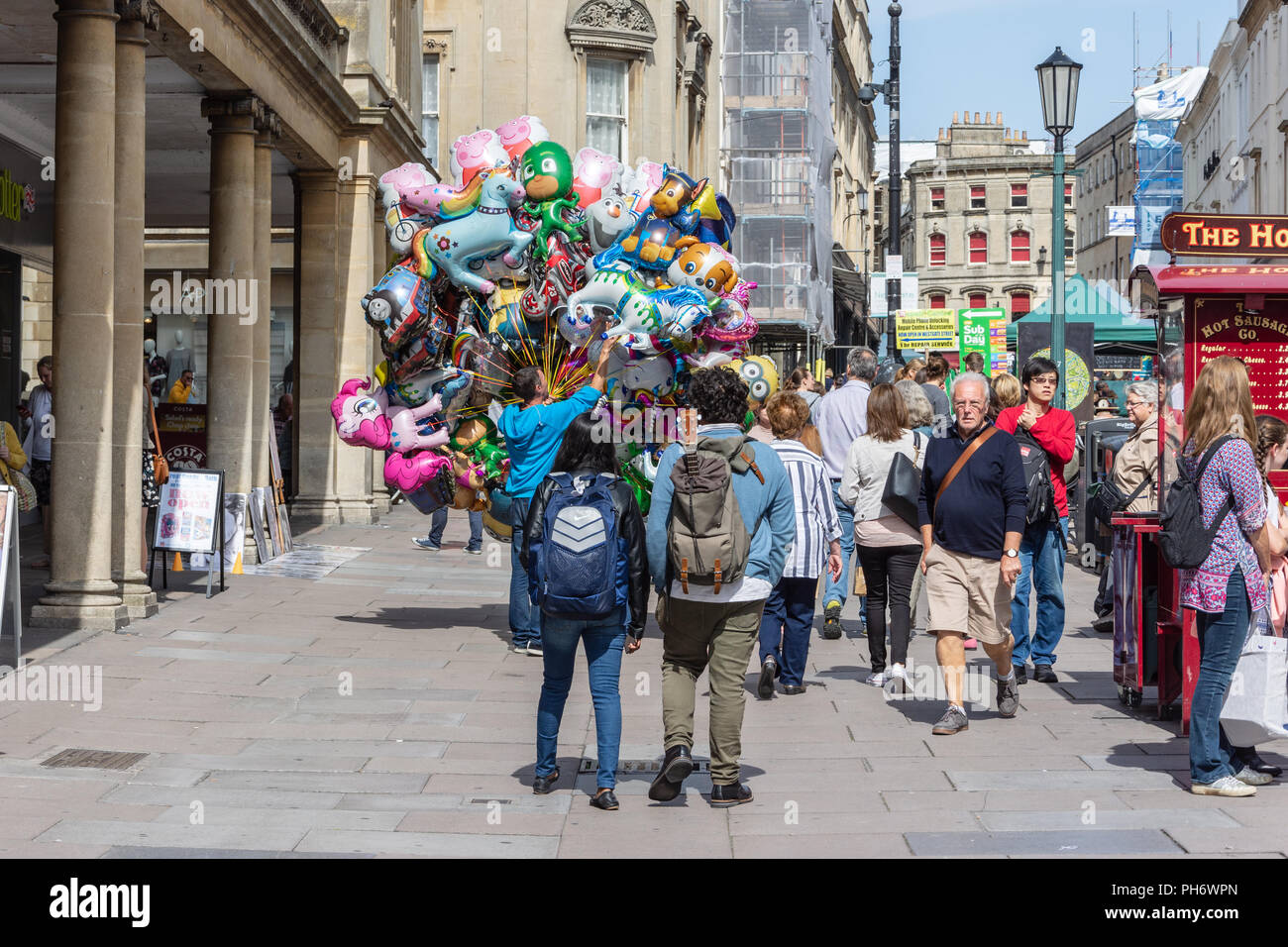 Vue arrière d'un vendeur de ballons gonflés à l'hélium de caractères lumineux dans la rue de décrochage la ville de Bath Banque D'Images