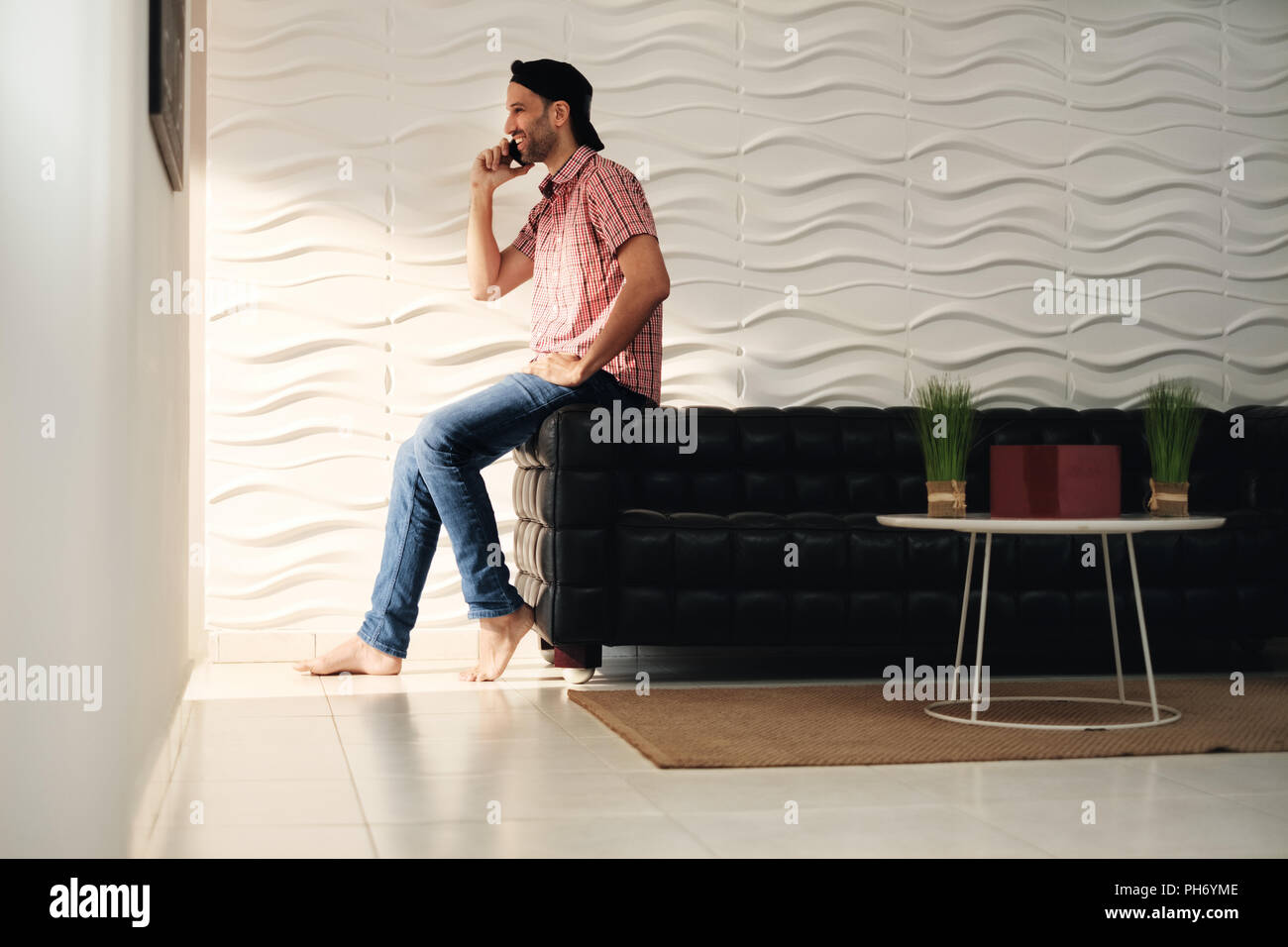 Jeune Latino Man Talking On Cell Phone At Home Banque D'Images