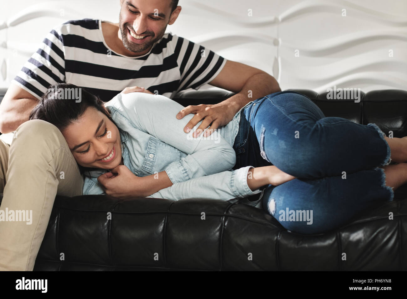 Image Couple Latino heureux de s'amuser et de rire sur le canapé Banque D'Images