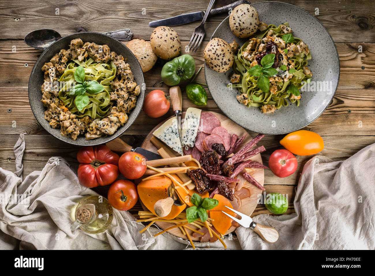 Pesto pâtes à la viande et aux champignons, une variété de fromages, viandes fumées et saucisses, légumes et herbes épicées sur une table en bois. Vue d'en haut Banque D'Images