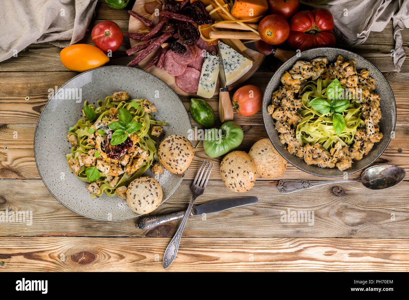 Pesto pâtes à la viande et aux champignons, une variété de fromages, viandes fumées et saucisses, légumes et herbes épicées sur une table en bois. Vue d'en haut Banque D'Images