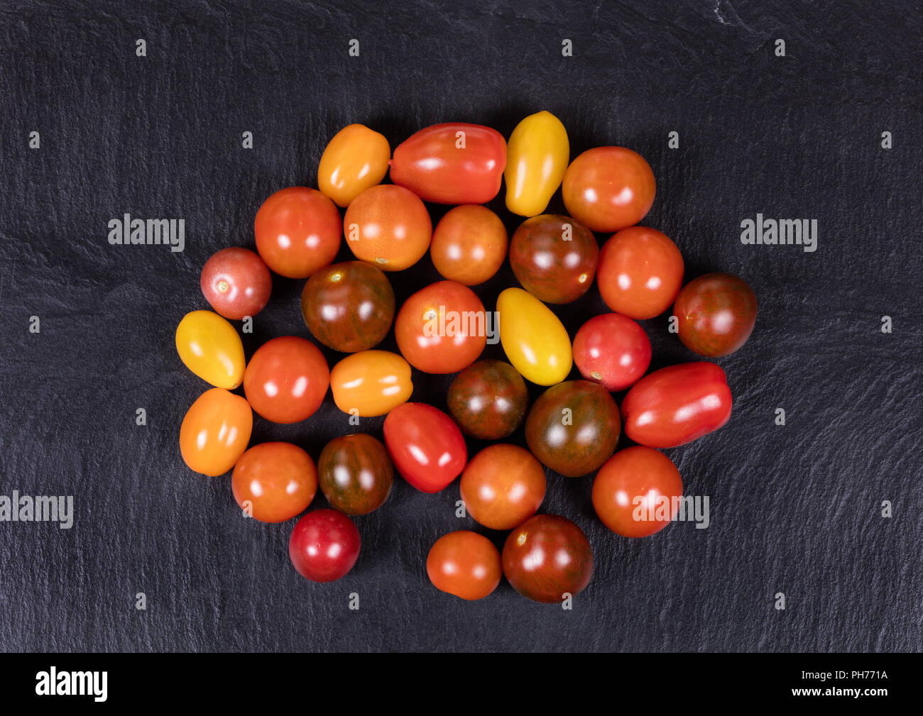 Mélange coloré petites tomates sur ardoise noir naturel Banque D'Images