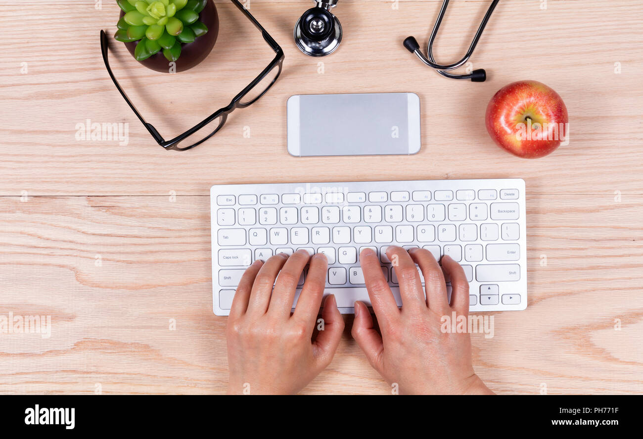 Les mains sur le clavier de l'ordinateur de bureau en bois Banque D'Images
