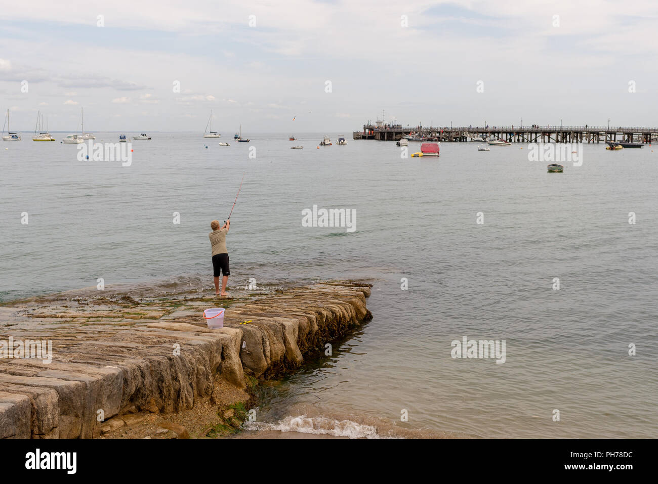 Garçon de pêche au large de la cale de pierre dans le port de Swanage, Dorset, UK Banque D'Images