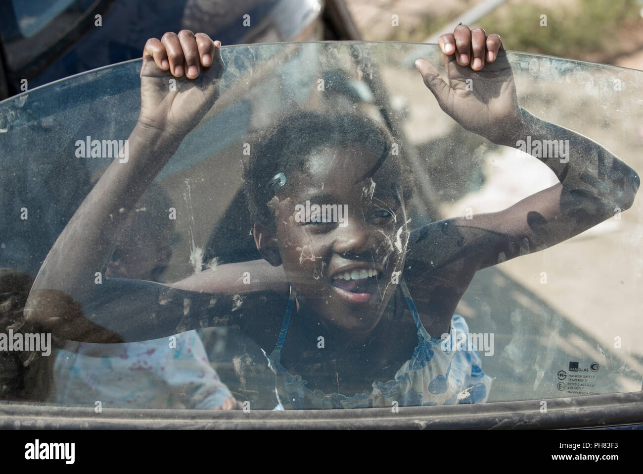 Une fille est la lecture d'une carcasse de voiture dans le quartier de taudis, Canton de Katutura, Windhoek, Namibie Banque D'Images