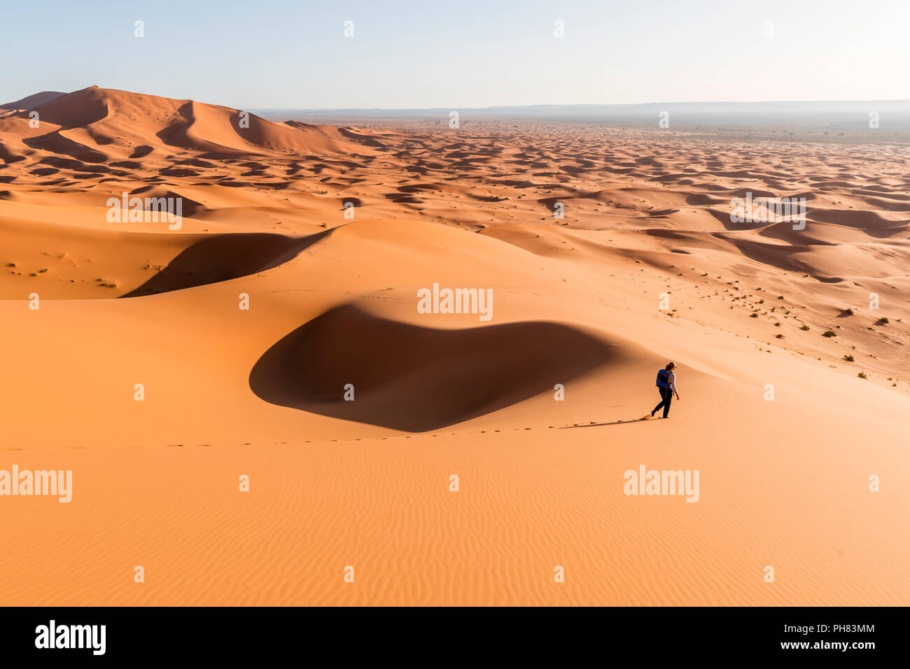 Woman running descente, dunes de sable rouge dans le désert, paysage de dunes Erg Chebbi, Merzouga, Sahara, Maroc Banque D'Images
