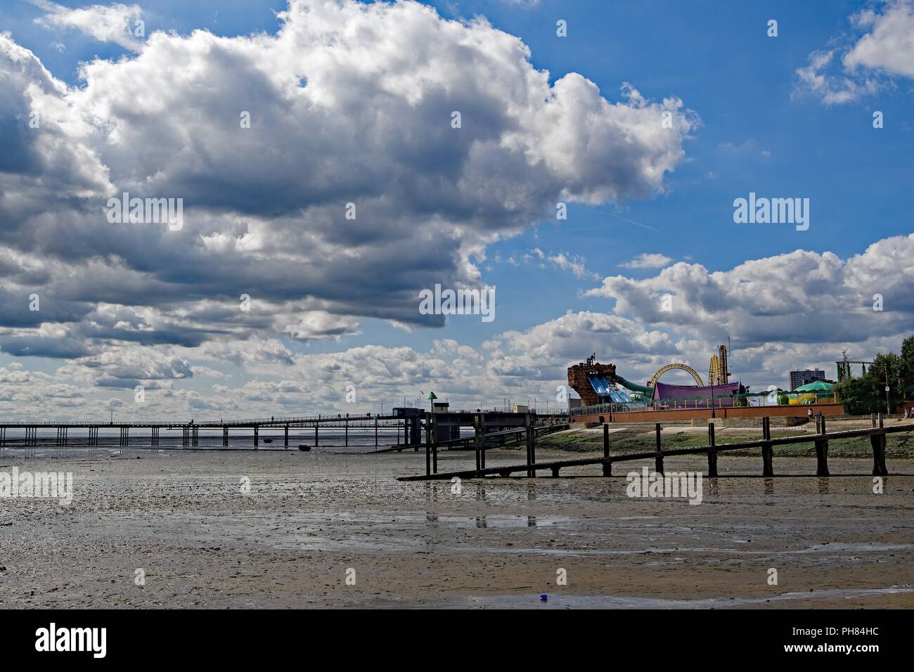 La capture d'énormes nuages blancs de rassemblement autour d'attractions, la plage à l'extrémité sud sur la mer, dans l'Essex. Banque D'Images