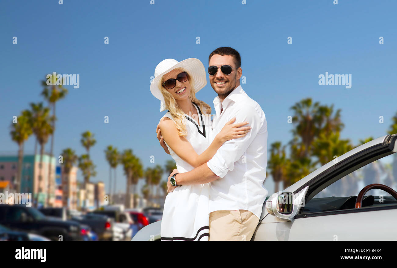 Heureux couple hugging près de voiture décapotable Banque D'Images