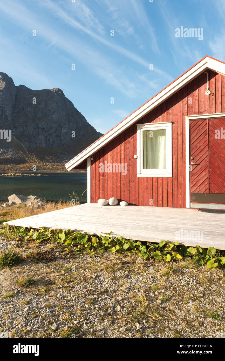 Close up portrait d'un Norvégien en bois cabane de plage avec des pierres sur le rivage avec vue sur le Fjord de Tromso, Cercle arctique, la Norvège et la montagne pe Banque D'Images