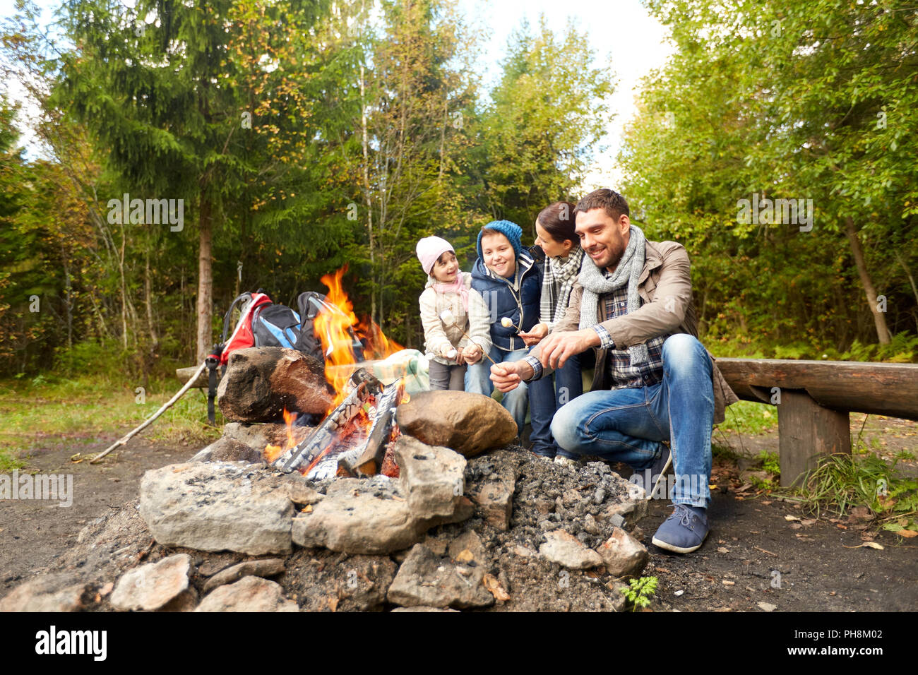 Famille heureuse le rôtissage de la guimauve sur feu de camp Banque D'Images